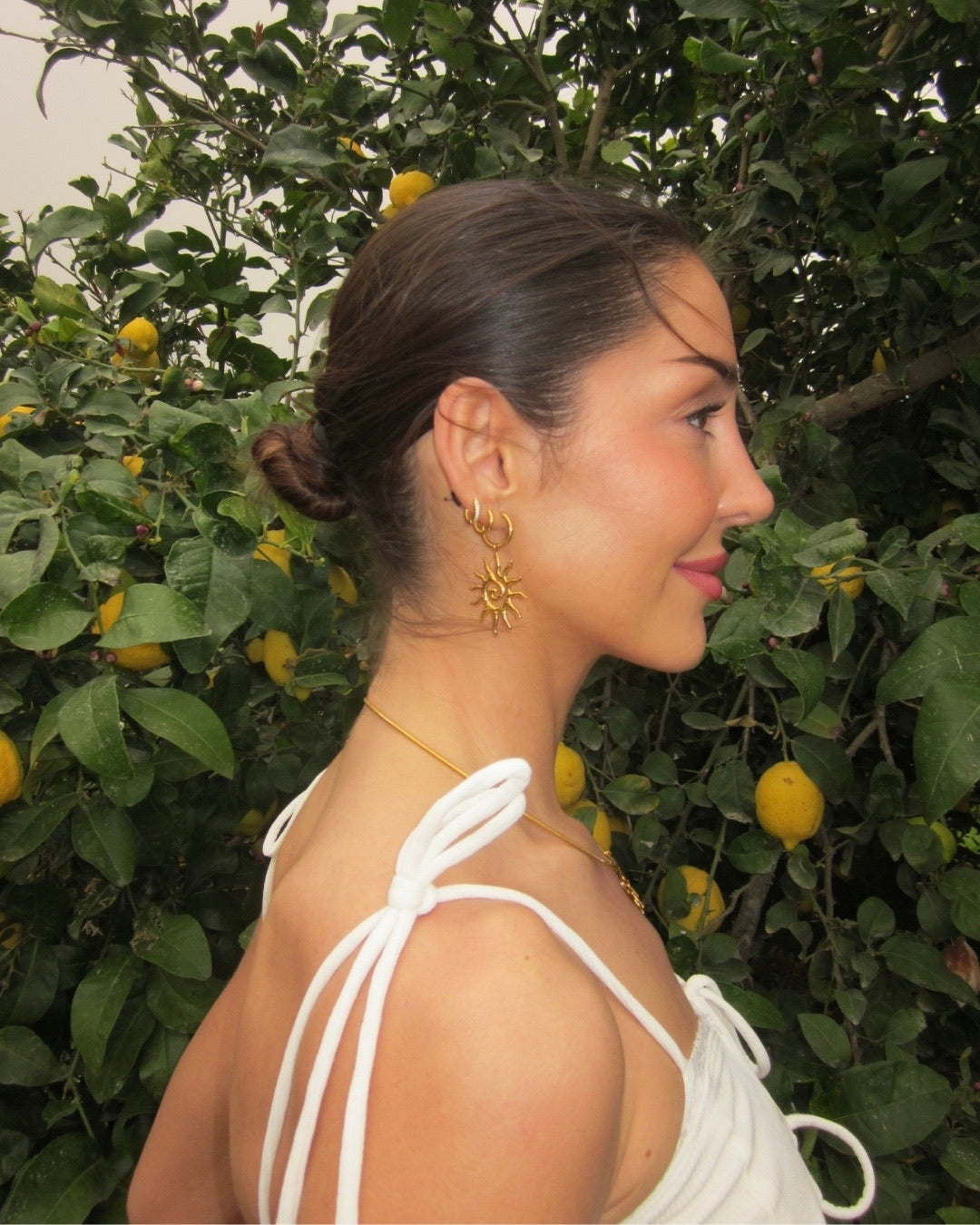 Närbild Solana Sun Earrings i guld bland citronträd – Alora Avenue sommarkollektion