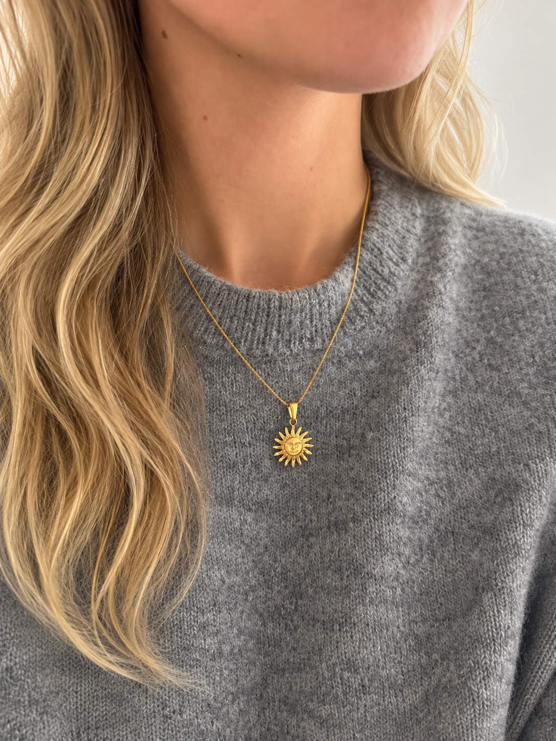 Solana Sun Pendant – solformat hänge i guld på tunn kedja, buret av modell. Vattentåligt guldsmycke från Alora Avenue.