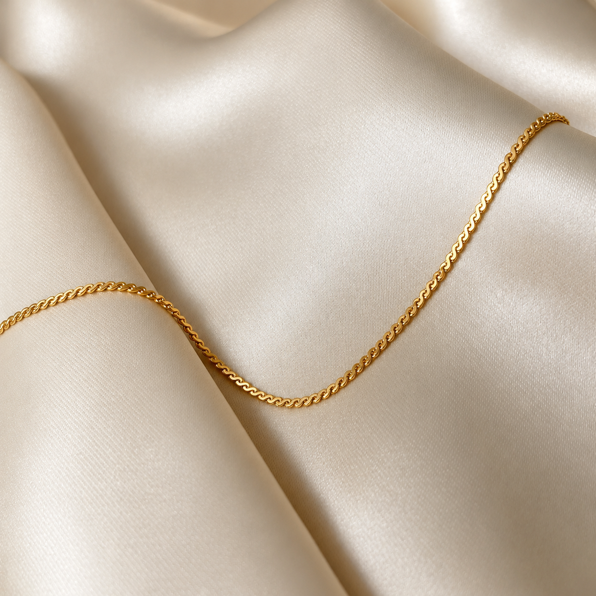 Sonya Saffron Bracelet i guld fotograferat på ljust silkestyg. Vattentåligt och allergivänligt armband i rostfritt stål med 18K PVD-guldplätering från Alora Avenue.