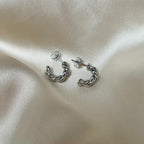Tornado Edge Earrings – tvinnade silverörhängen i rostfritt stål från Alora Avenue. Fotade på mjuk sidenbakgrund. Vattentåliga, eleganta och perfekta för både vardag och fest.