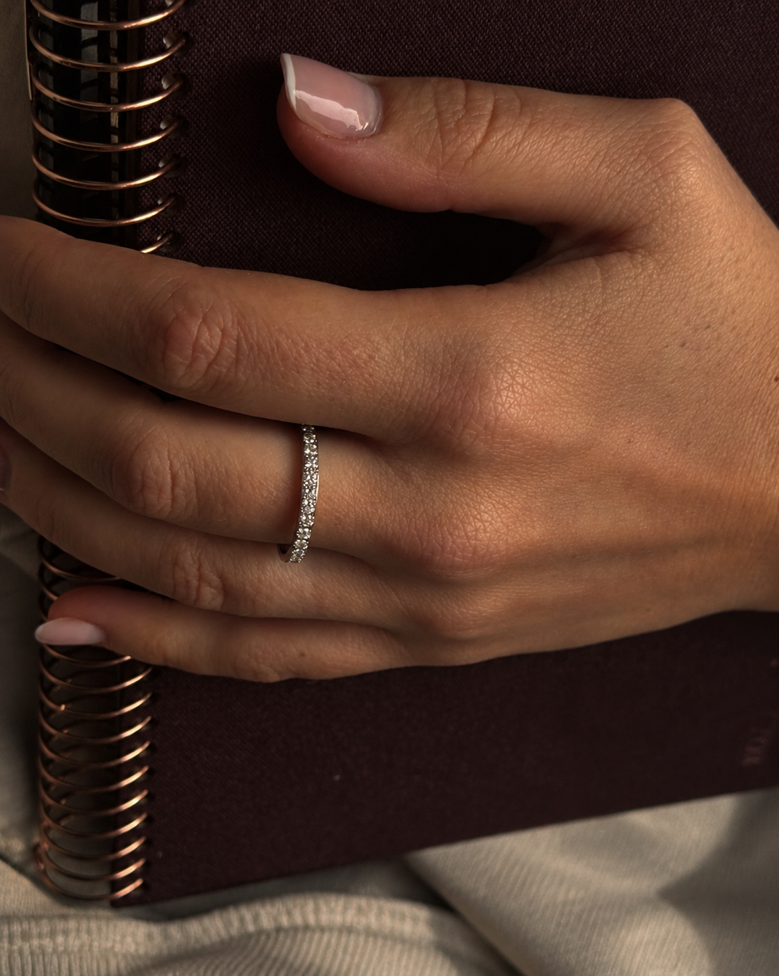 Twinkle Thea Ring i silver på modellens hand mot en anteckningsbok – tunn stenring med cubic zirconia för vardagsbruk. Vattentålig, allergivänlig ring i rostfritt stål från Alora Avenue.