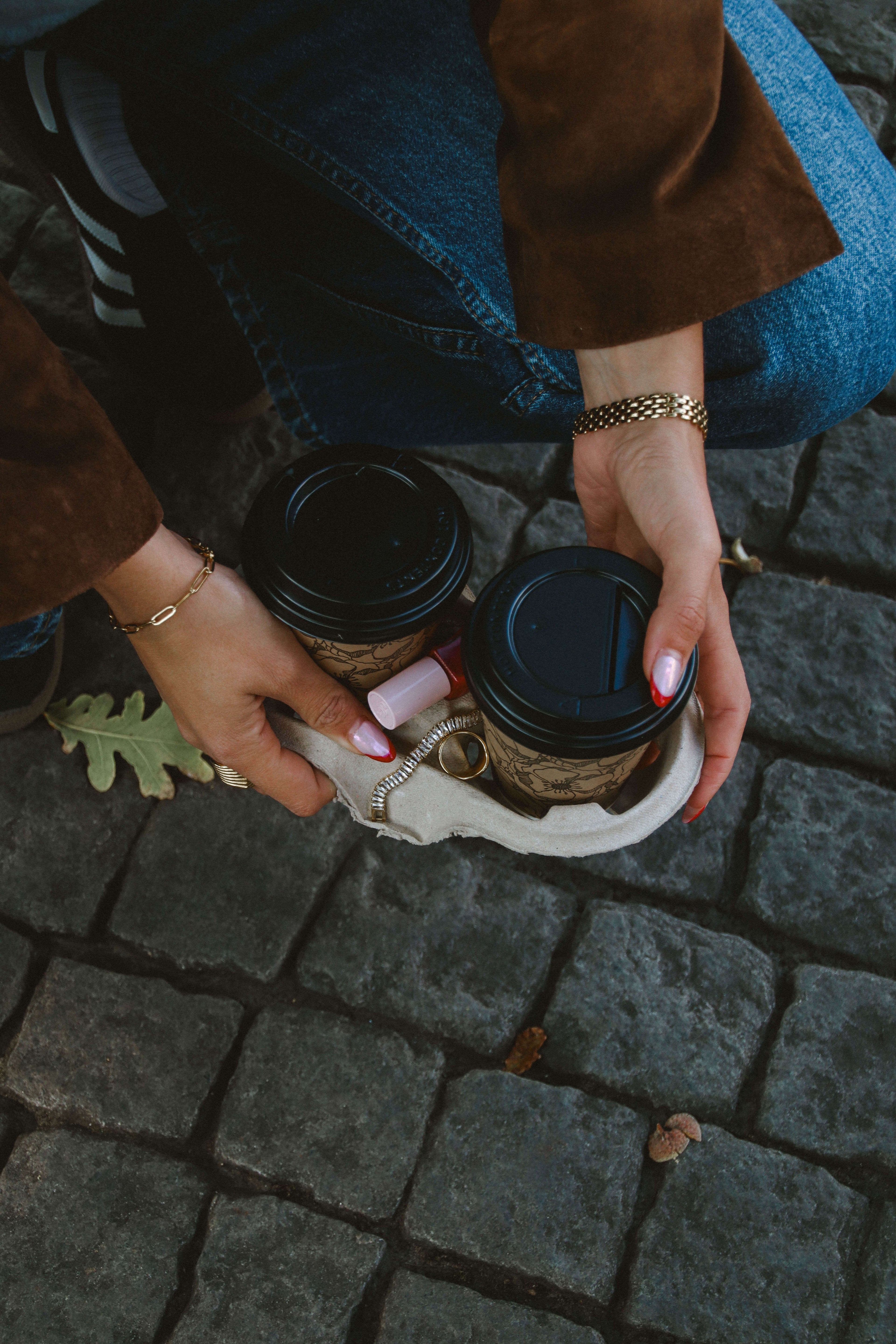Närbild på vattentåliga smycken i guld från Alora Avenue – kedja och armband i rostfritt stål med PVD-plätering, kombinerade med kaffe och höstoutfit för vardagslyx.