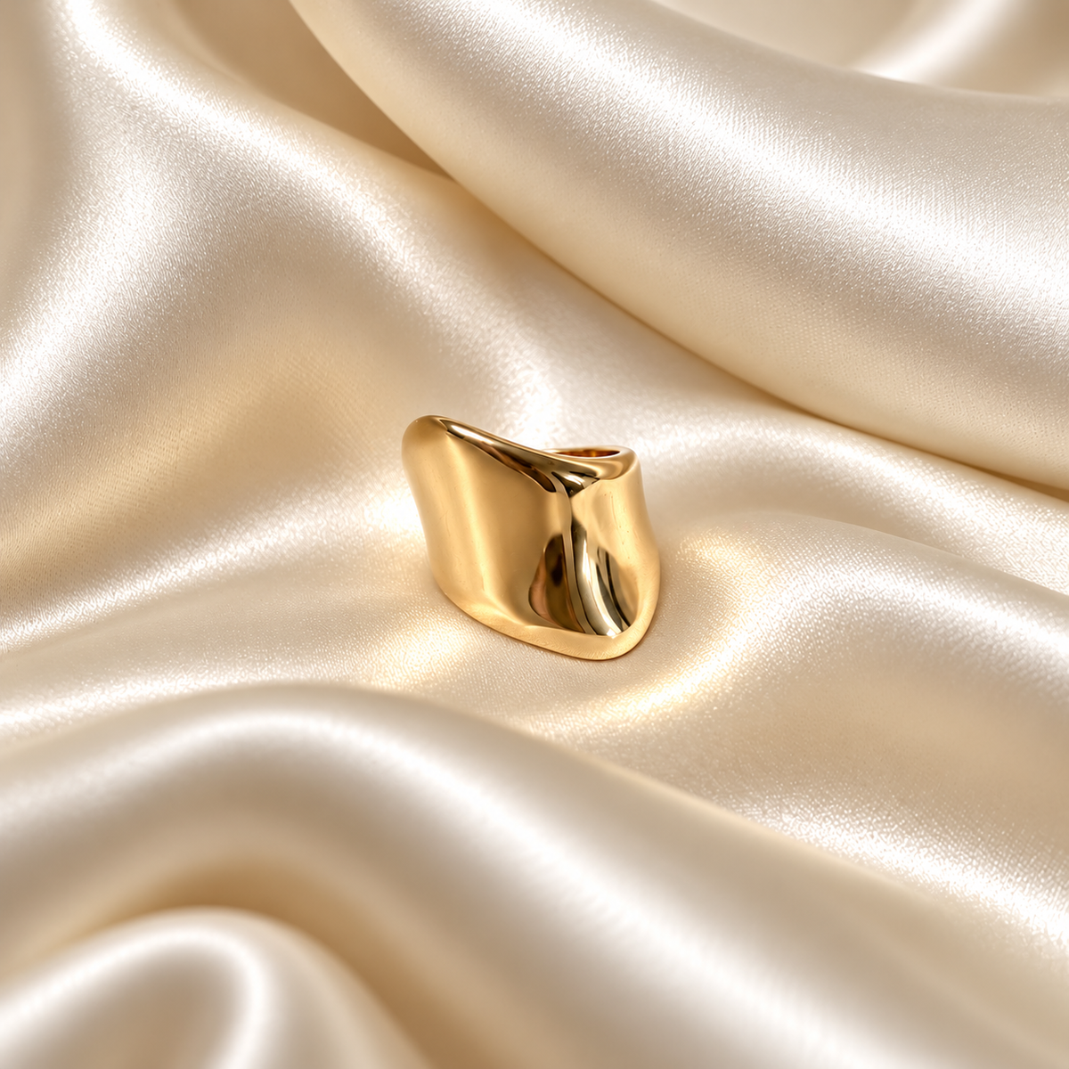 Violet Volume Ring i guld fotograferad på ljust silkestyg. Vattentåligt och allergivänligt smycke i rostfritt stål med 18K PVD-guldplätering från Alora Avenue.
