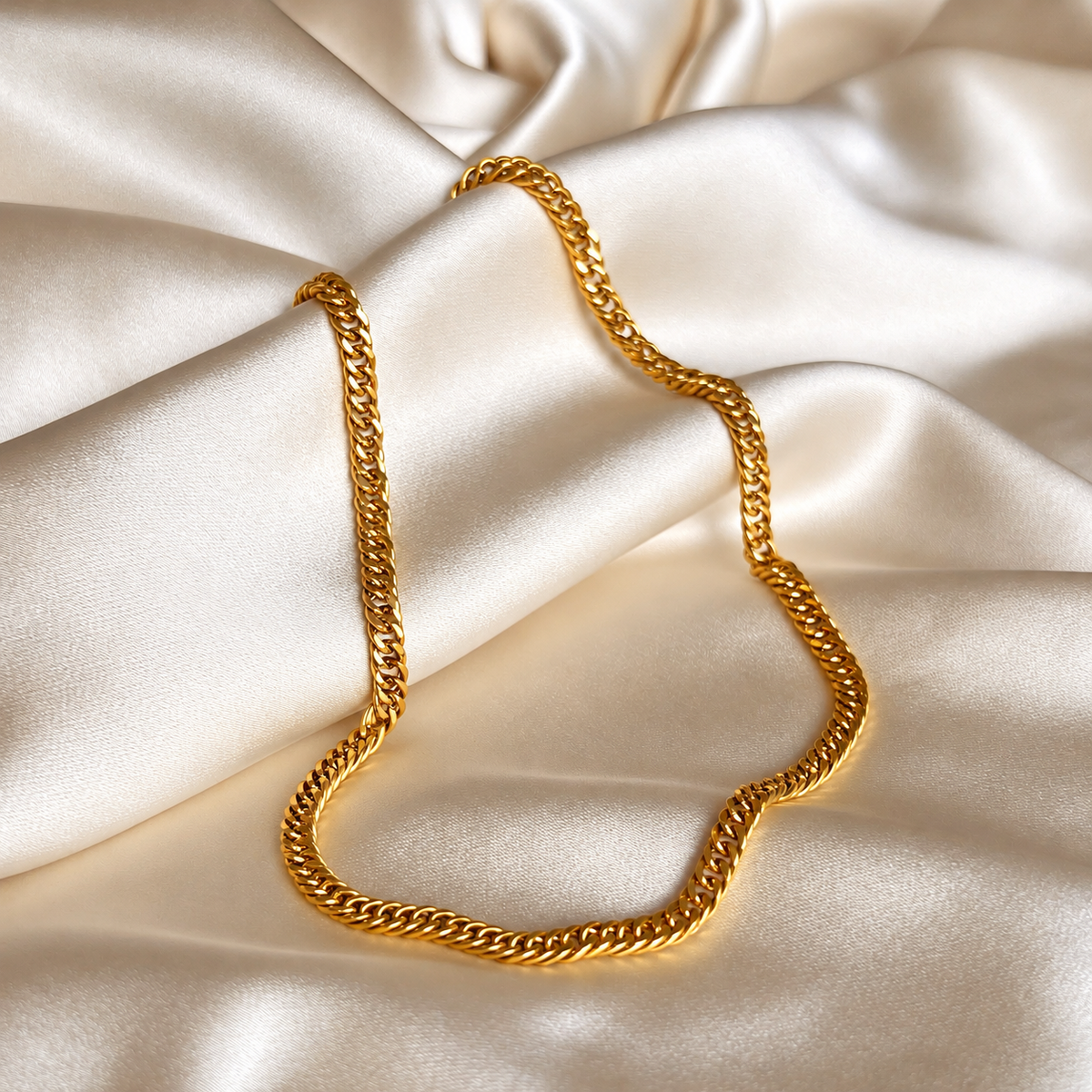 Zion Everest Necklace i guld fotograferat på ljust silkestyg. Vattentåligt och allergivänligt halsband i rostfritt stål med 18K PVD-guldplätering från Alora Avenue.